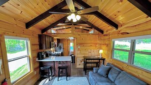 A cozy cabin interior with a kitchen, dining area, and a sofa. - Bmv6 Tiny Home Topline (Twin Mountain)