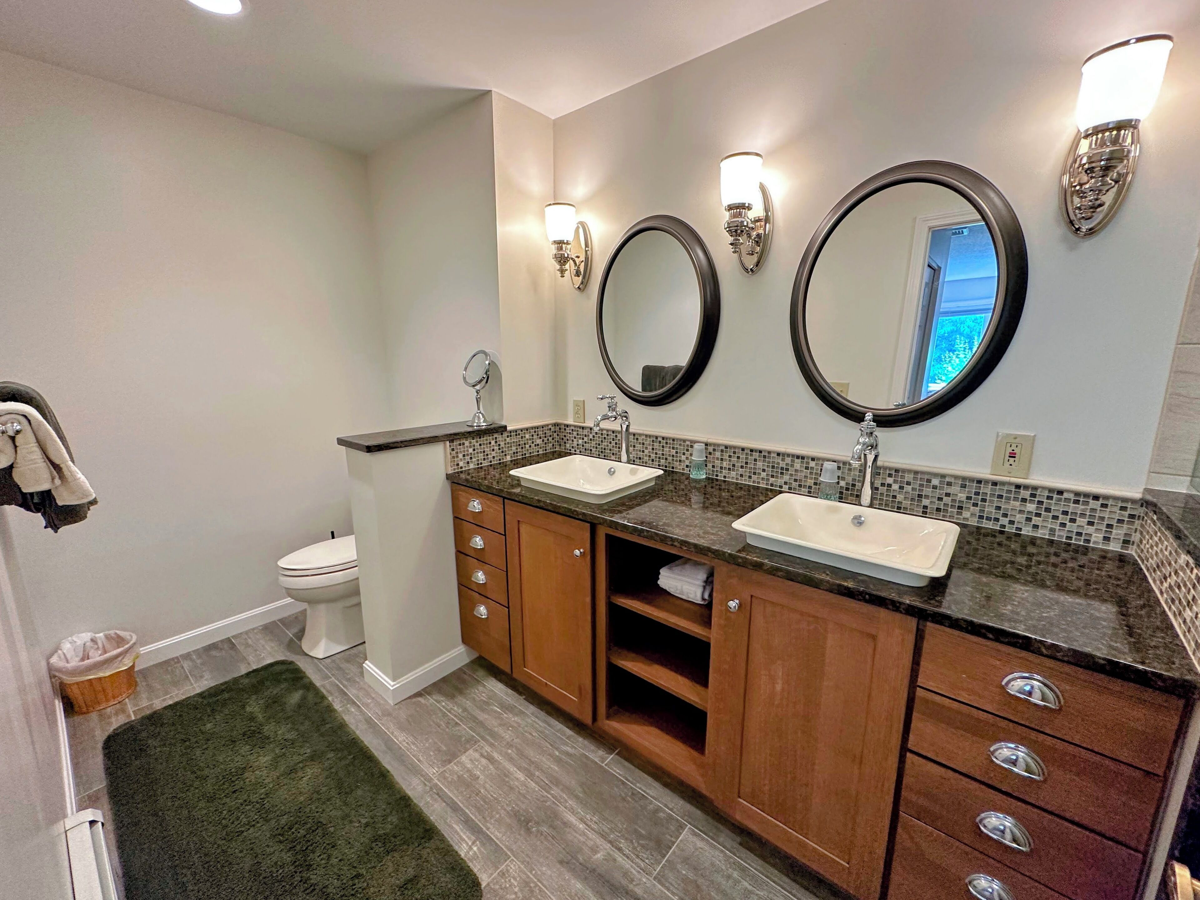 A bathroom with two sinks, a toilet, and a mirror.