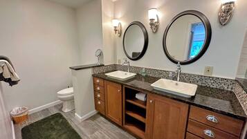 A bathroom with two sinks, a toilet, and a mirror.