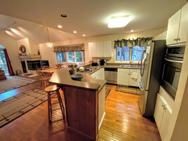 Una cocina moderna con una isla central, electrodomésticos de acero inoxidable y un comedor con chimenea.
