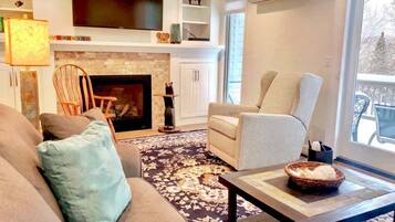 A living room with a fireplace, a television, a sofa, a chair, and a coffee table.