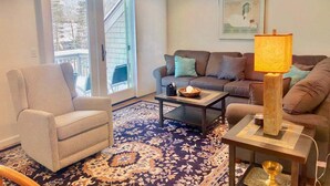 A living room with a sofa, armchair, coffee table, and a lamp. - R21 Completely Renovated Bretton Woods Condo, AC, Unbeatable Ski-in Ski-out Location! Fast Wifi (Bretton Woods)