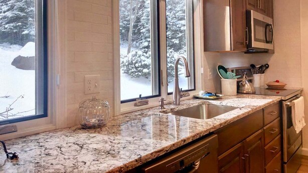 A kitchen with a granite countertop, stainless steel appliances, and a window with a snowy view. - R21 Completely Renovated Bretton Woods Condo, AC, Unbeatable Ski-in Ski-out Location! Fast Wifi (Bretton Woods)