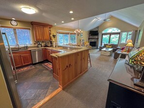 A spacious kitchen with wooden cabinets, a large island, and a dining area with a fireplace. - Fv27 Luxurious Mt Washington Hotel Golf Course Home! (Bretton Woods)