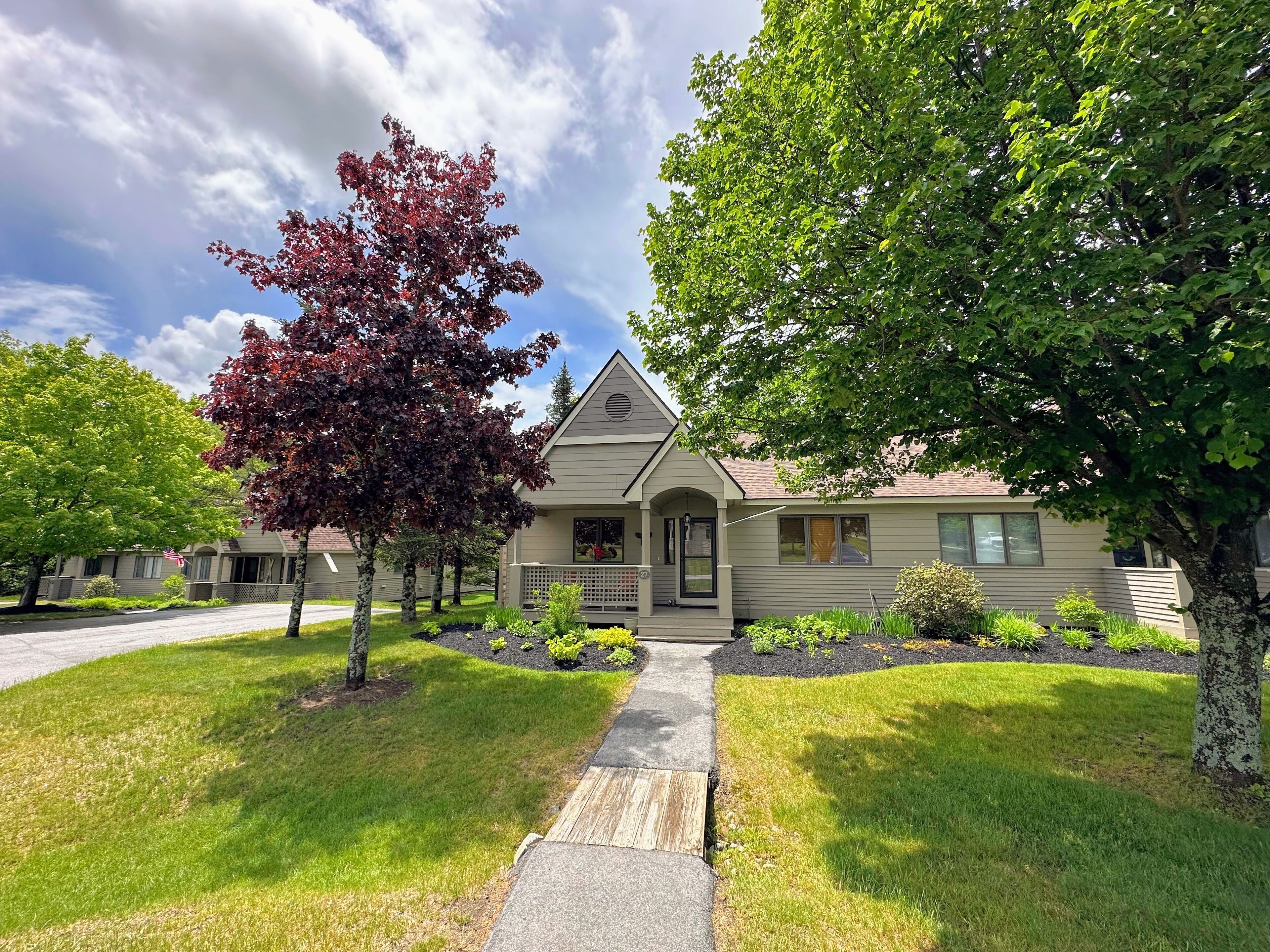 A single-story house with a front porch, a small garden, and a clear sky.