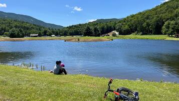 Une scène au bord d’un lac, avec un vélo et une personne assise près de l’eau.