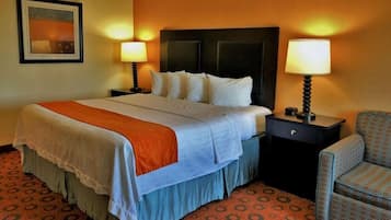 Habitación de hotel con cama, dos mesitas de noche con lámparas, una silla y alfombra estampada.