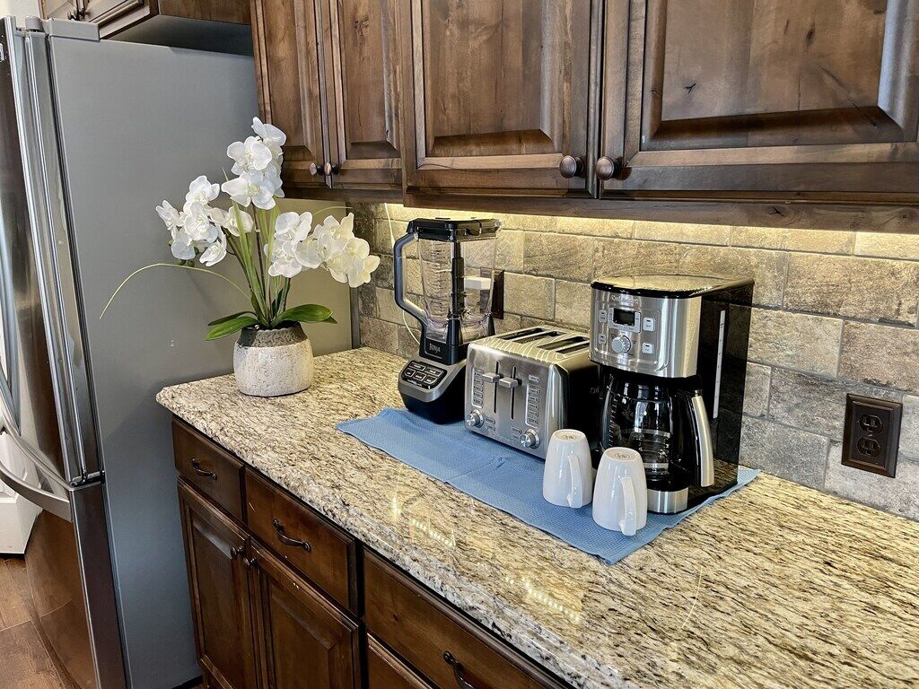 A kitchen with granite countertops, a coffee maker, a toaster, and a potted orchid.