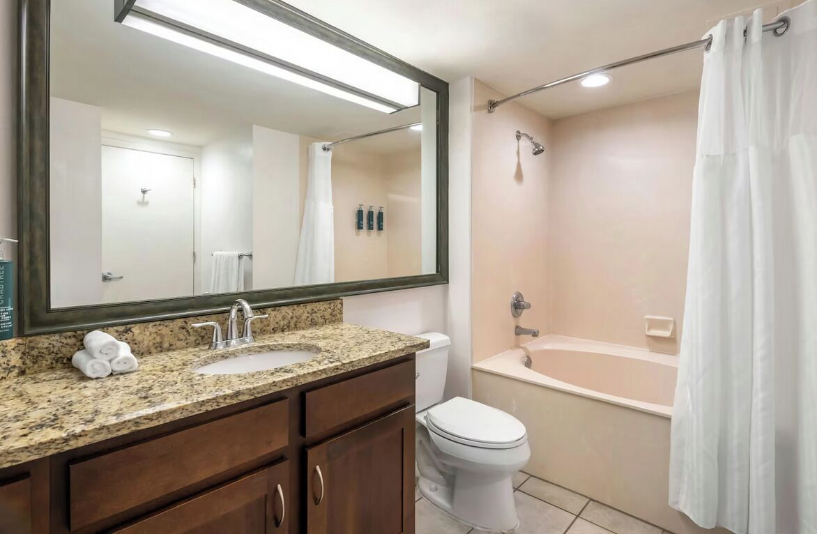 Een badkamer met een wastafel, toilet, bad en douche.
