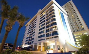 Ein mehrstöckiges Hotel mit modernem Design, mit Balkonen auf jeder Etage und einem gut beleuchteten Eingang.