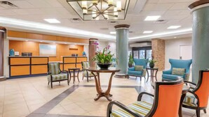 A hotel lobby with a reception desk, seating area, and decorative plants. - Best Place to Stay for the Jeep Beach Week at Daytona Beach, FL - 1 BD/1 BA (Daytona Beach)