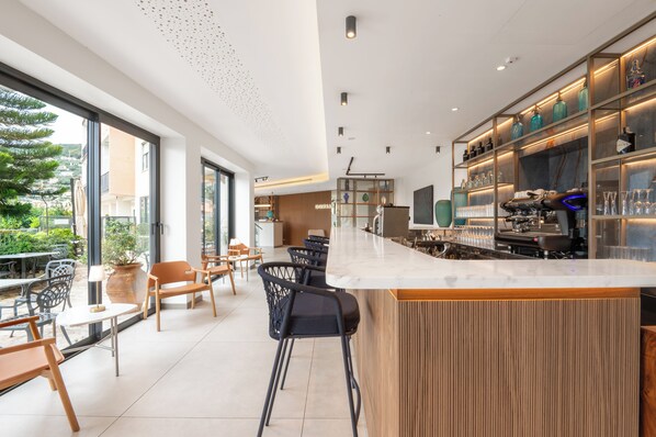 Eine moderne Bar mit einer Marmorplatte, schwarzen Barhocker und einer Glasvitrine.