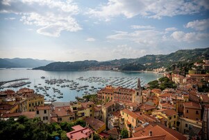 Un pueblo costero con edificios históricos, un puerto deportivo y montañas al fondo.