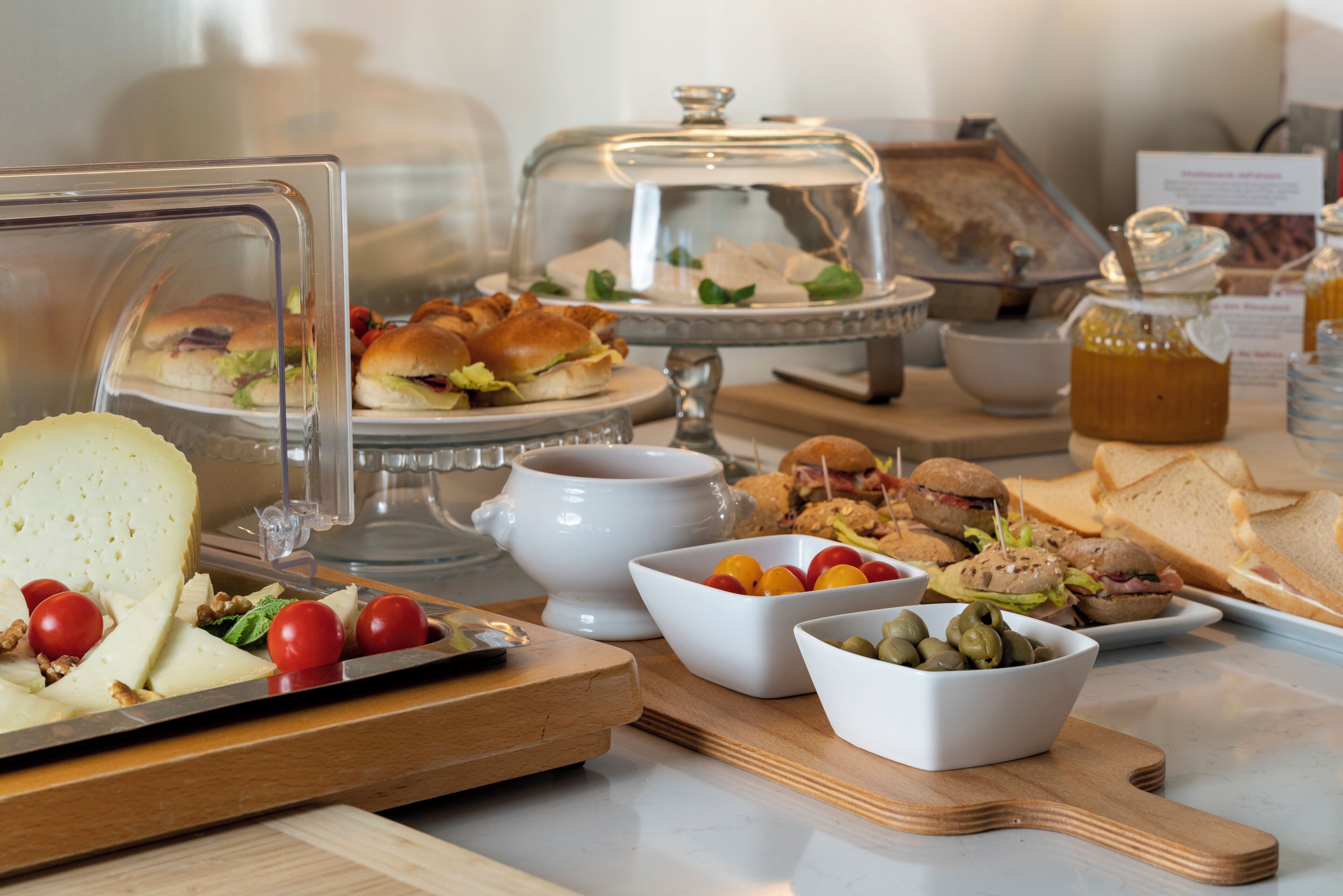 Een buffet met diverse gerechten, waaronder belegde broodjes, salades en kaas.