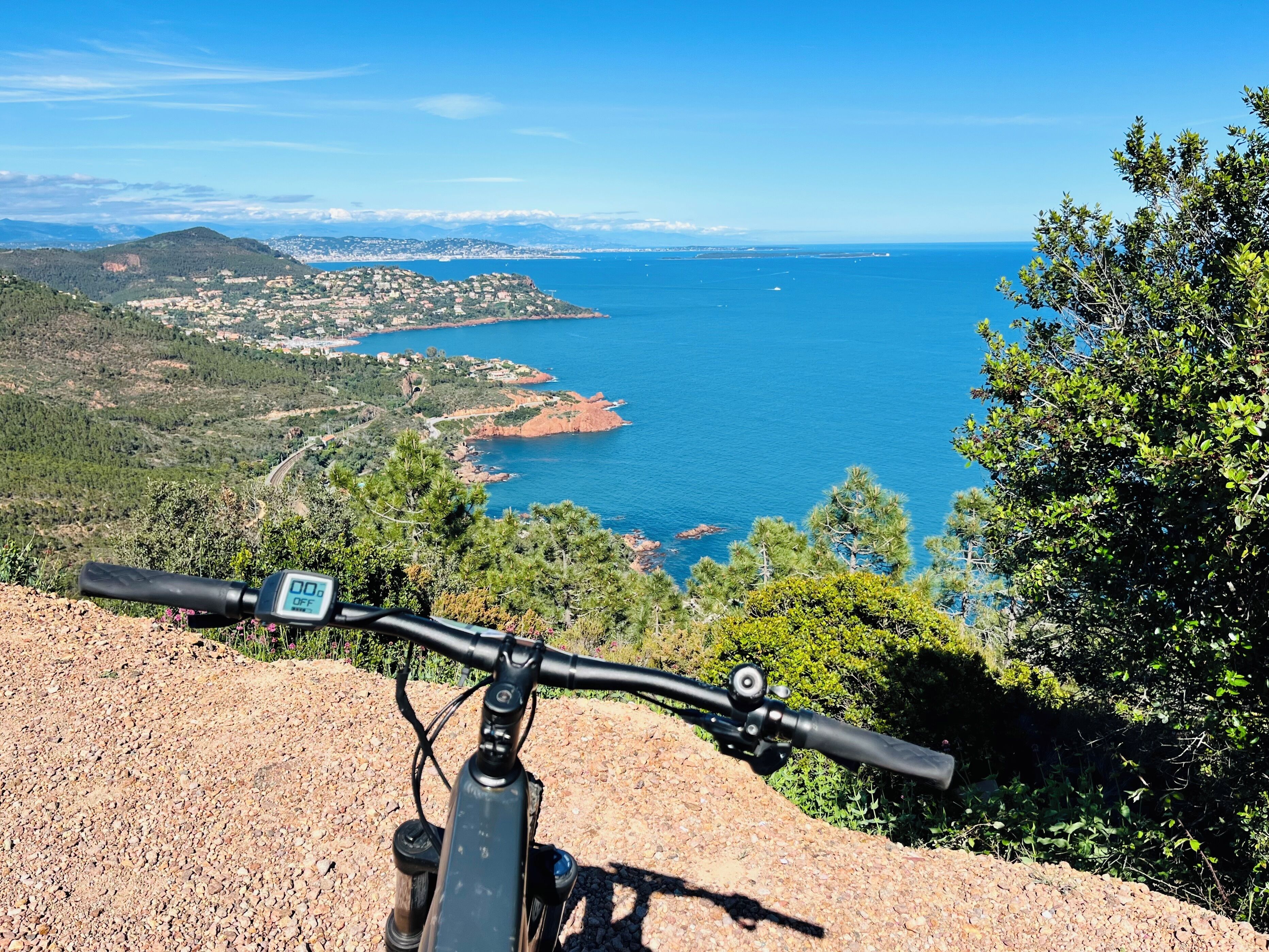 A mountain bike on a rocky path with a scenic view of a coastal town and the sea.