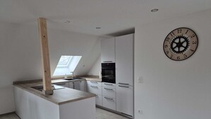 Una cocina moderna con una isla central, electrodomésticos integrados y un reloj de pared.