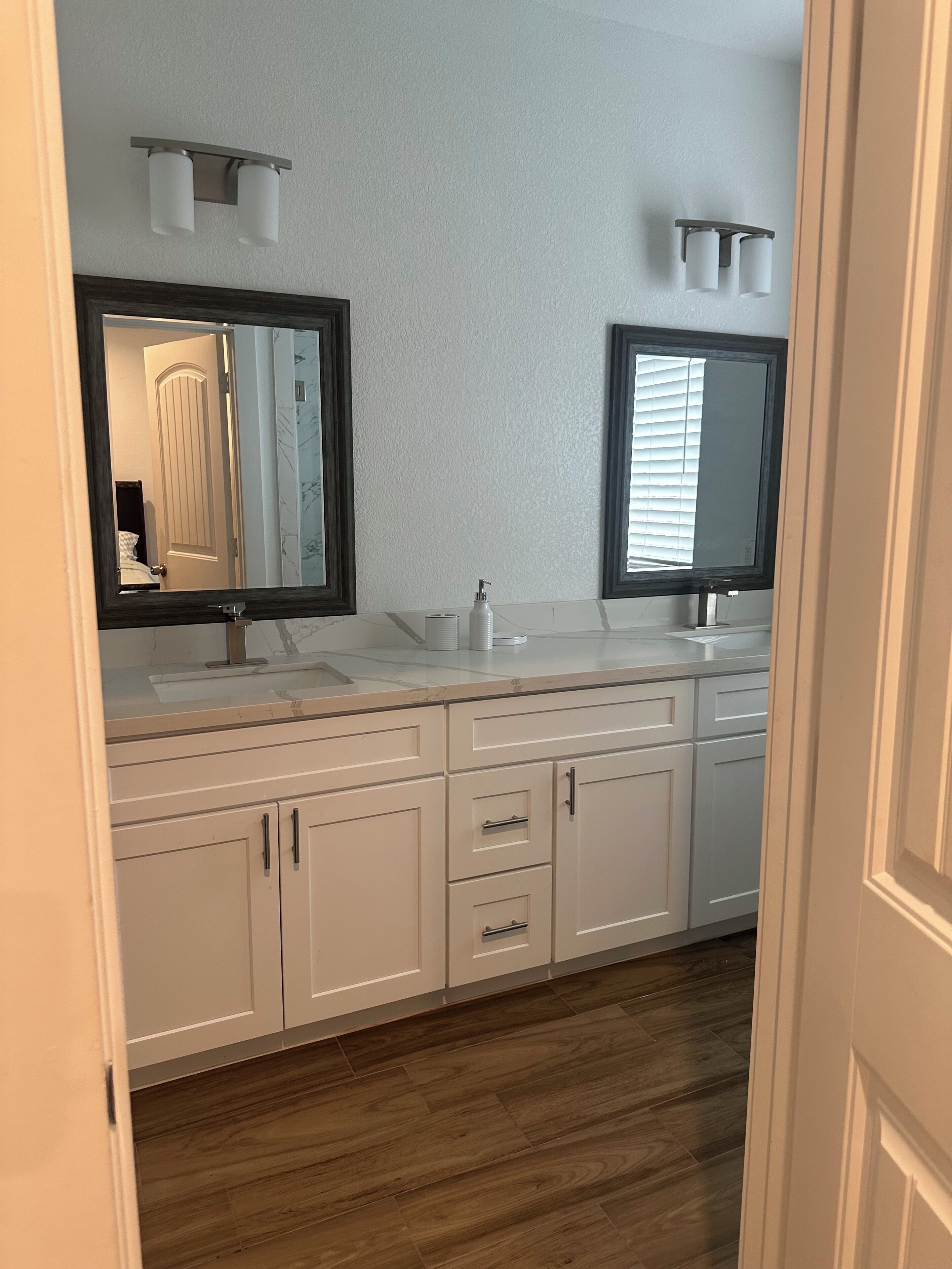 Une salle de bain avec deux lavabos, un grand miroir et un plancher en bois.