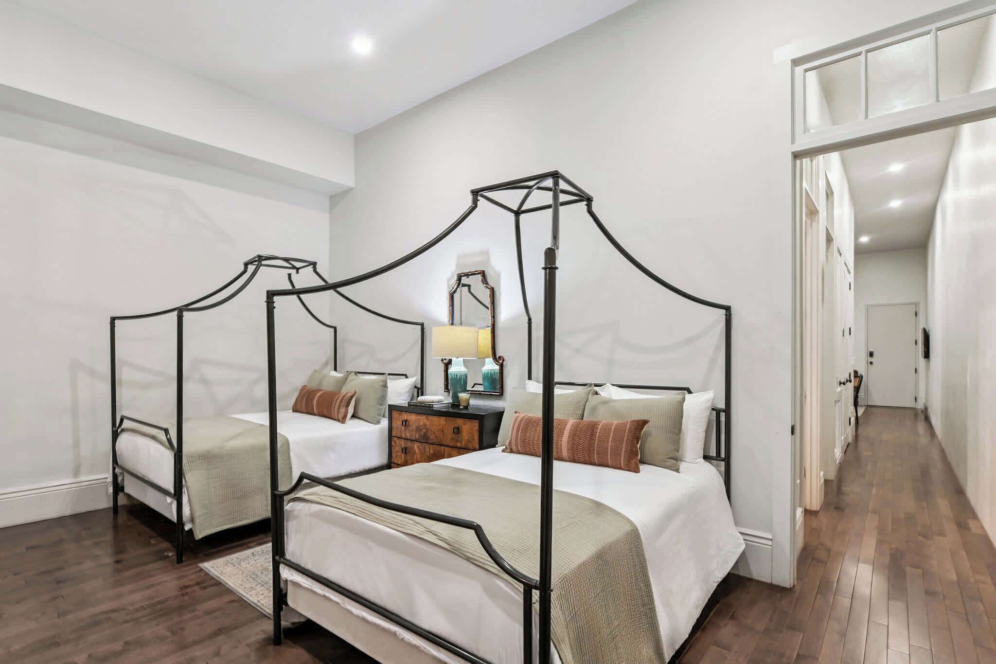 A four-poster bed with a nightstand, a mirror, and two bedside tables in a hotel room.