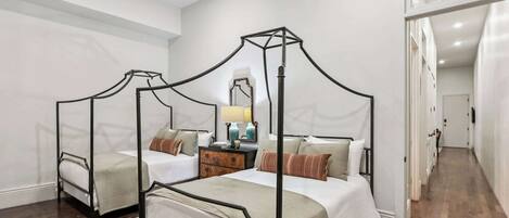 A four-poster bed with a nightstand, a mirror, and two bedside tables in a hotel room.
