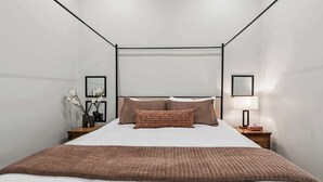 Um quarto moderno com uma cama grande, duas mesas de cabeceira e uma luminária na parede.