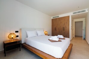 Et moderne hotelværelse med en stor seng, et træhovedgærde, to sengeborde med lamper og et klædeskab.