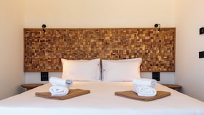 Hotellihuone, jossa on suuri sänky, kaksi tyynyä, puinen pääty ja kaksi yöpöytää, joilla on pyyhkeitä.