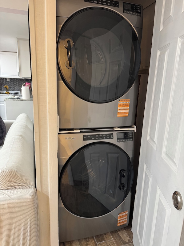 A compact washer and dryer unit with a control panel, placed in a narrow space between a door and a wall.
