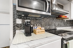 A compact kitchen with a microwave, kettle, and a coffee maker.