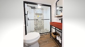 A modern bathroom with a glass-enclosed shower, white toilet, and a wooden floor. - Cozy 1BR in Philly with Rain Shower (Philadelphia)