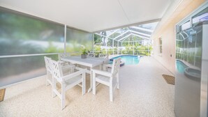 Un espace extérieur abrité, doté d’une piscine, de mobilier blanc et de grandes fenêtres.