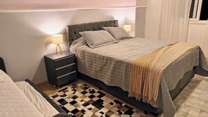 Ein Schlafzimmer mit einem Bett, Nachttischen, einer Lampe und einem gemusterten Teppich.