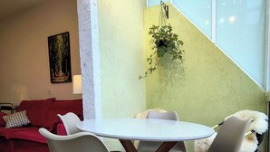 Ein Essbereich mit einem runden Tisch, vier Stühlen, einem roten Sofa und einem Gemälde an der Wand.
