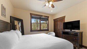 Ein Schlafzimmer mit einem Bett, einem Fernseher, einem Deckenventilator, einem Fenster und einem Kleiderschrank.