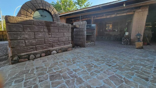 Une terrasse en pierre avec un mur en briques et un four en pierre.