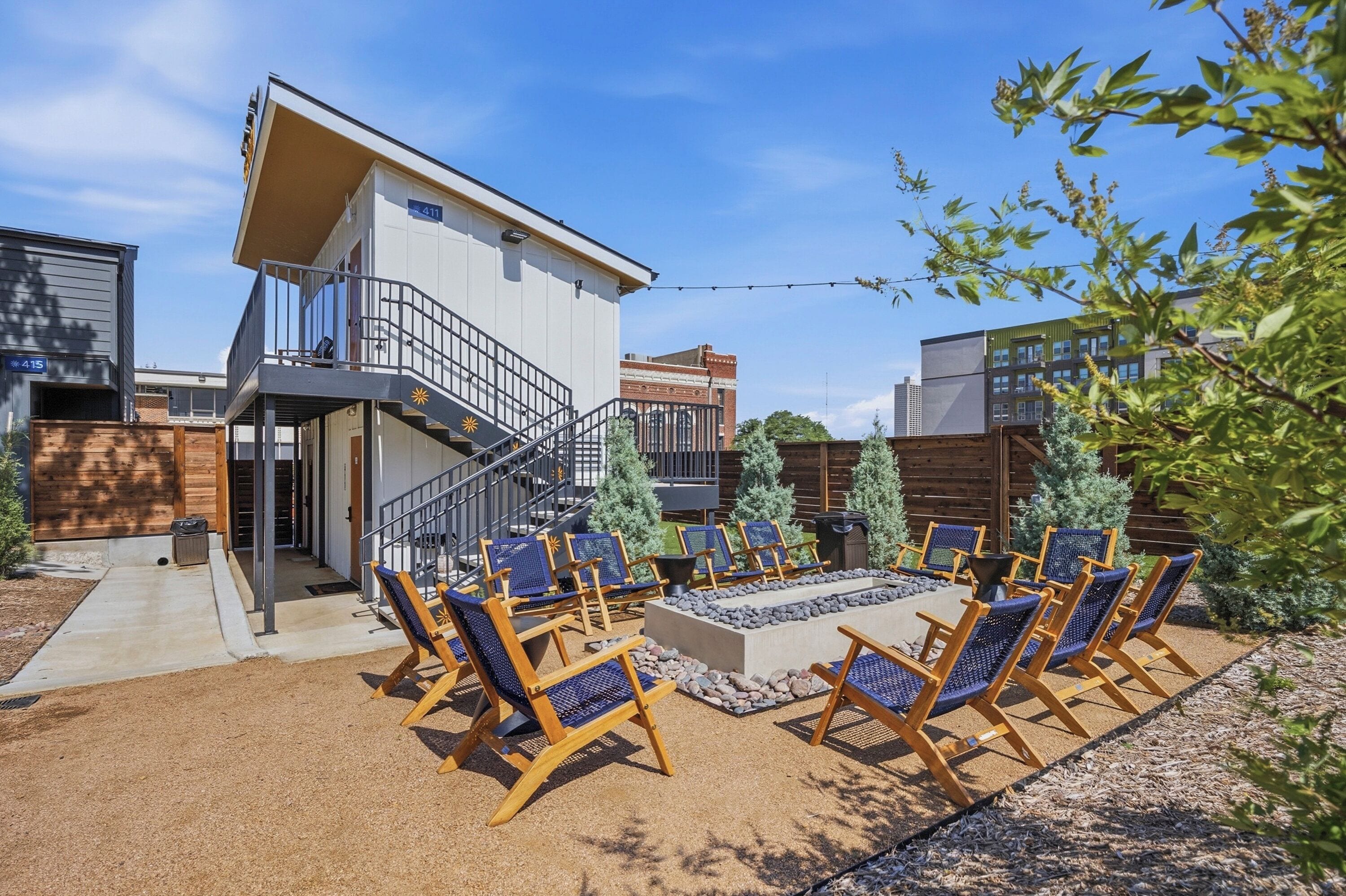 A modern building with a balcony and a patio area with outdoor seating.