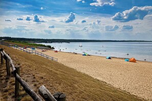 A beach with tents and a sailboat.