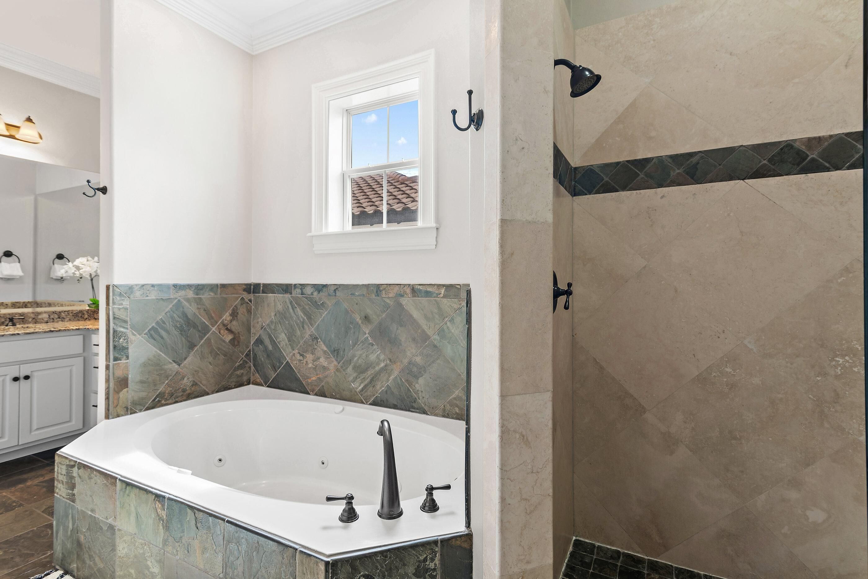A modern bathroom with a freestanding bathtub, a shower area, and a window providing natural light.
