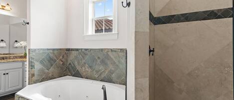 A modern bathroom with a freestanding bathtub, a shower area, and a window providing natural light.