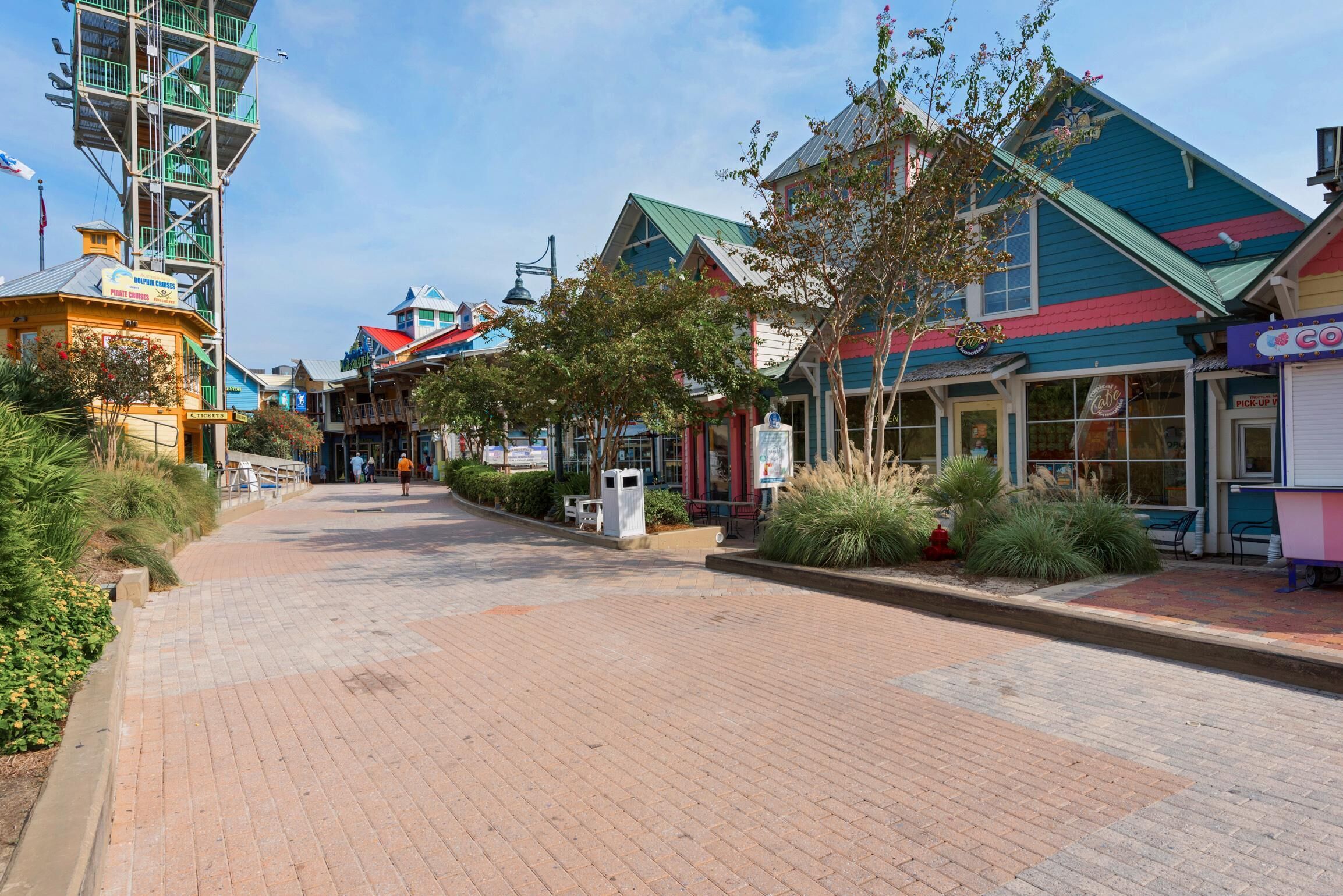 A paved street lined with colorful buildings, including a blue and red building with a sign that reads "COCO".