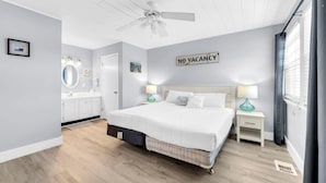 A modern bedroom with a bed, bedside tables, a vanity with a mirror, and a 'NO VACANCY' sign. - Lullwater Beach 415 (Panama City Beach)