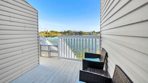 A balcony with wicker furniture and a view of a lake. - Lullwater Beach 415 (Panama City Beach)