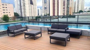 A rooftop pool area with modern lounge chairs and a view of high-rise buildings. - Studios with outdoor pool in the lounge. (São Paulo)