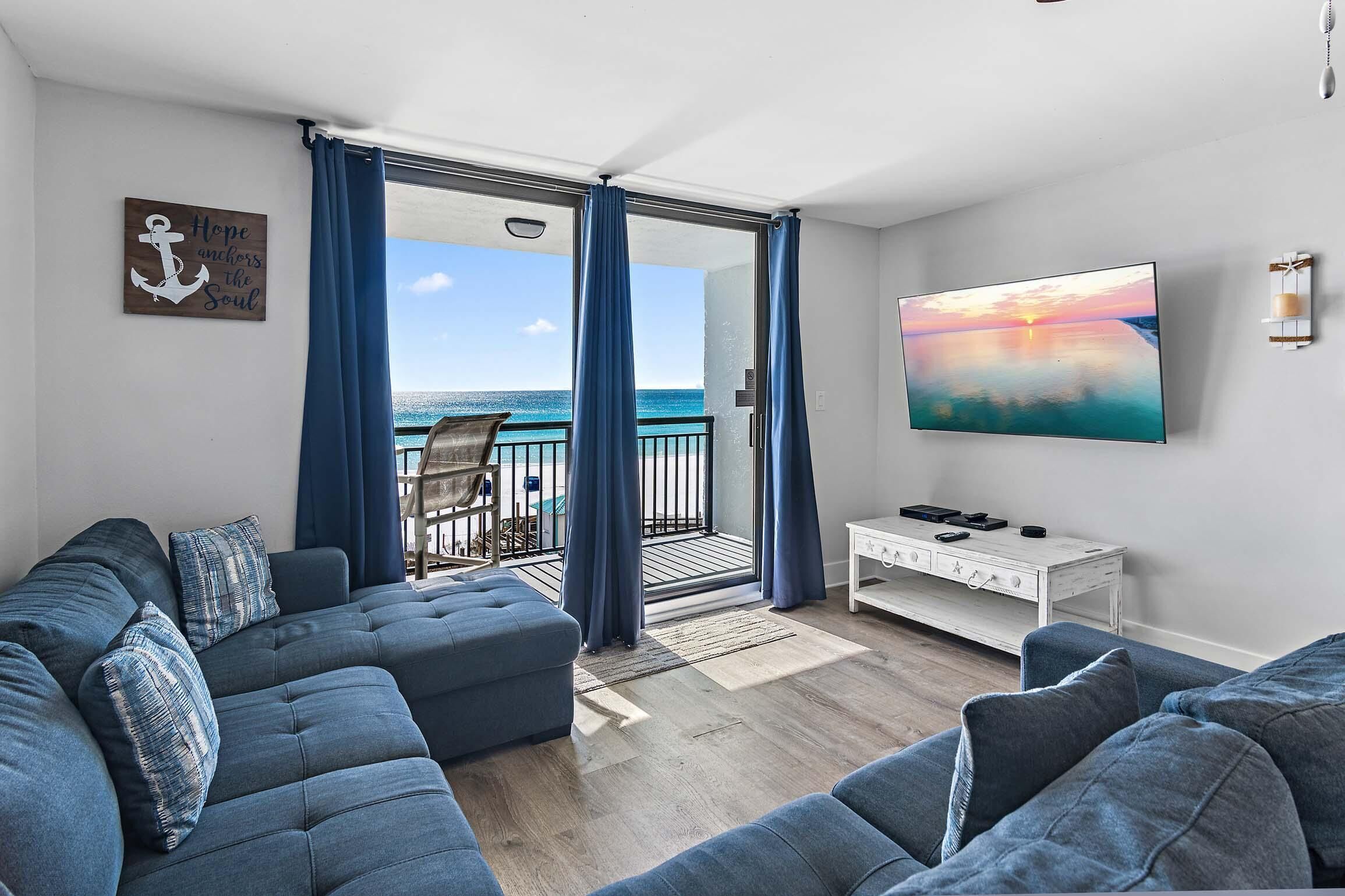 Un salon moderne avec un grand canapé, une table basse et un tableau représentant un coucher de soleil.