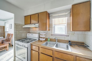 A kitchen with wooden cabinets, a stove, a sink, and a window. - Red Line to Airport! Inviting Home in Cleveland (Cleveland)