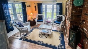 Una habitación acogedora con muebles de mimbre, una mesa redonda y una chimenea de ladrillo.