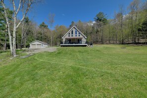 A two-story house with a large front porch, a garage, and a grassy yard surrounded by trees. - Mount Vision Home for Cooperstown Baseball Fams (Mt Vision)