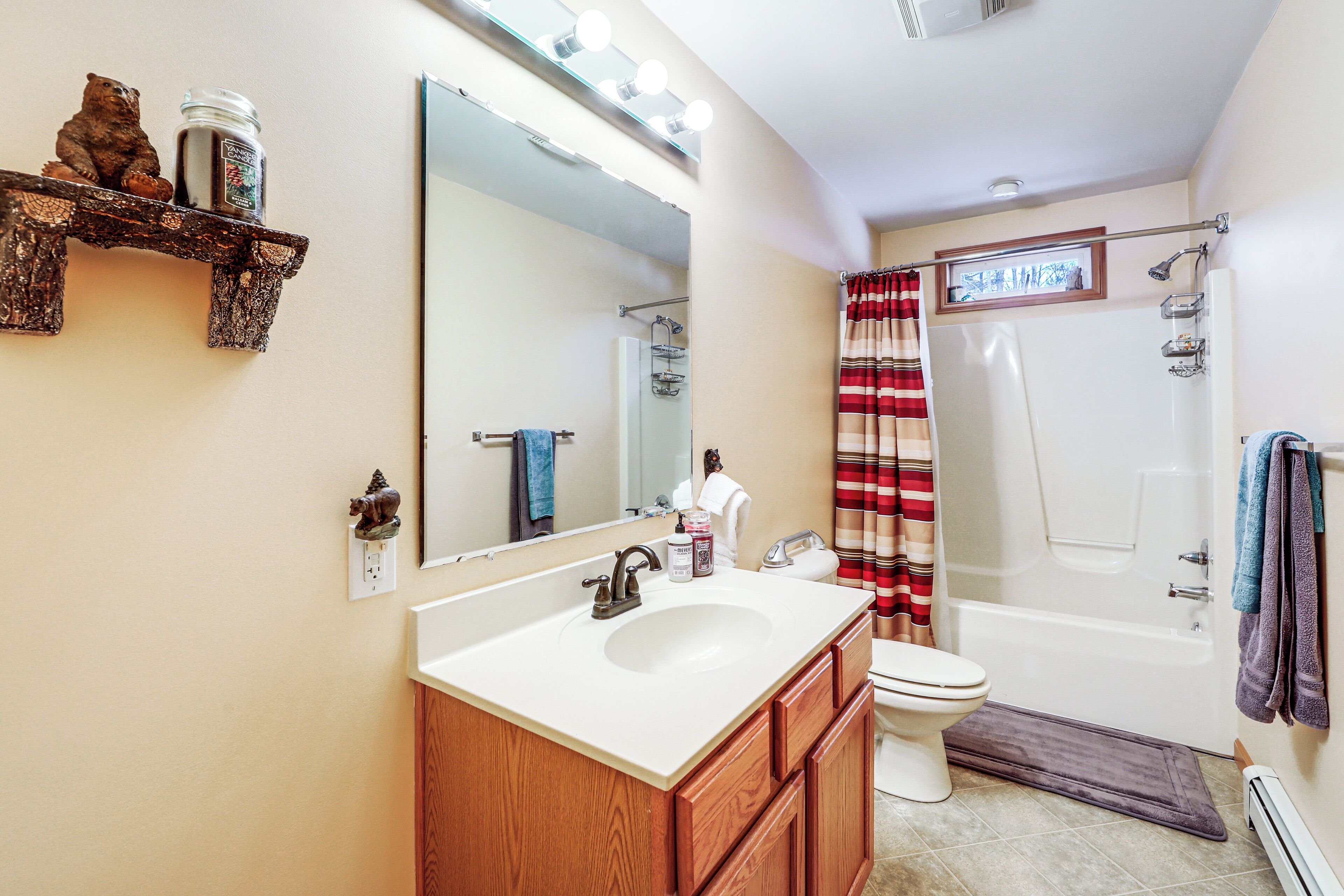 A bathroom with a large mirror, a sink, a toilet, and a shower.