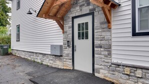 A house with a stone foundation, a wooden porch, and a white door. - Walk to Lititz Springs Park: Cozy Getaway! Apt 2 (Lititz)