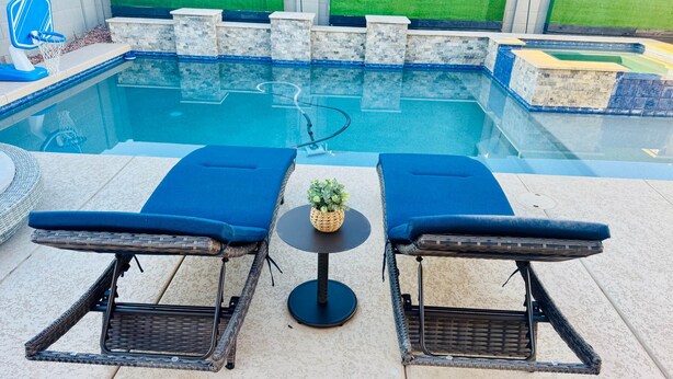 A poolside area with two lounge chairs, a small table with a plant, and a clear view of the pool. - Homes by Abby LLC (Maricopa)
