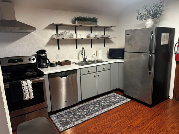 Una cocina compacta equipada con lavavajillas, estufa, refrigerador y microondas.